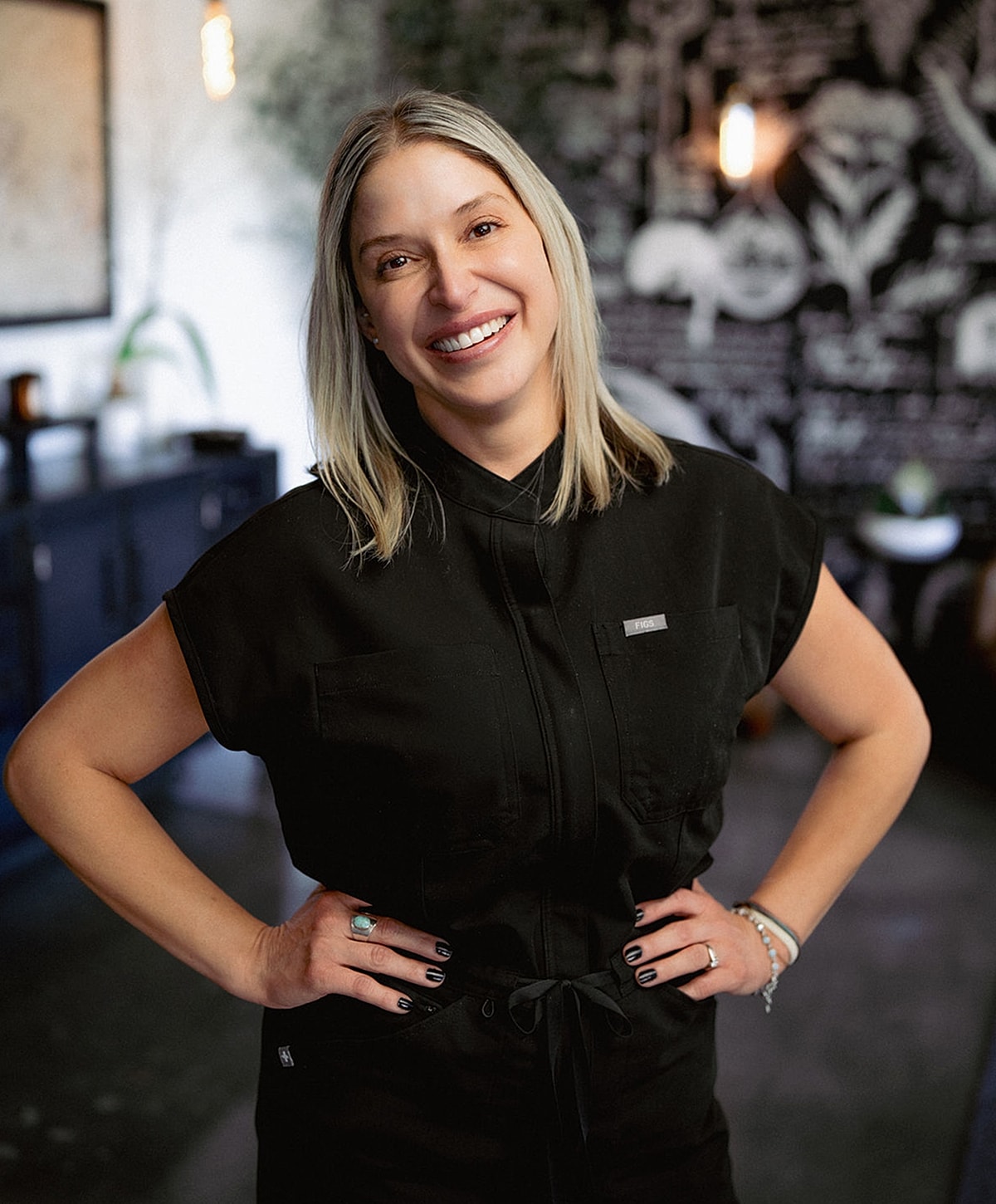 Smiling woman posing in stylish black outfit.