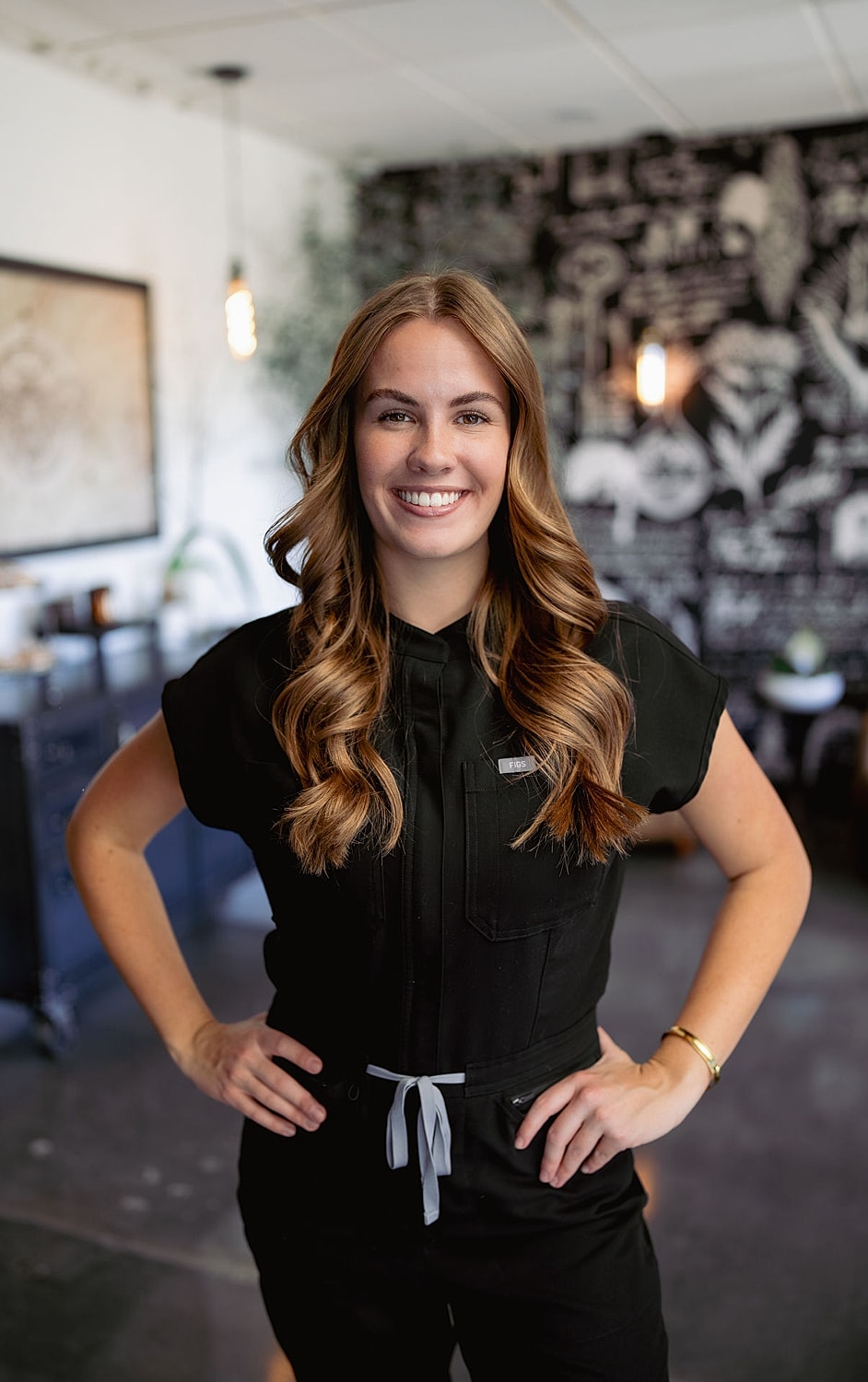 Woman smiling in black outfit, modern background.