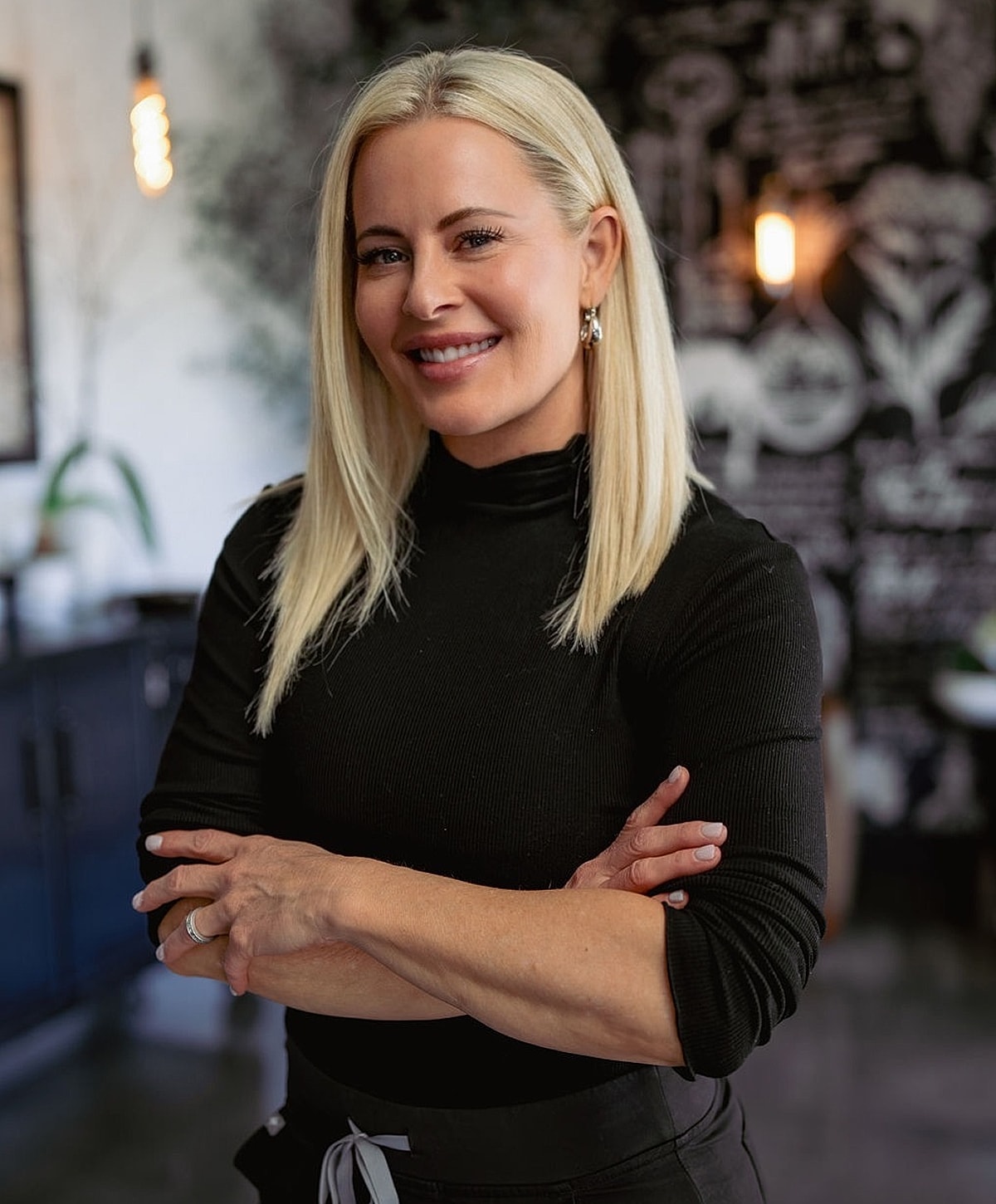 Smiling woman with blonde hair in black outfit.