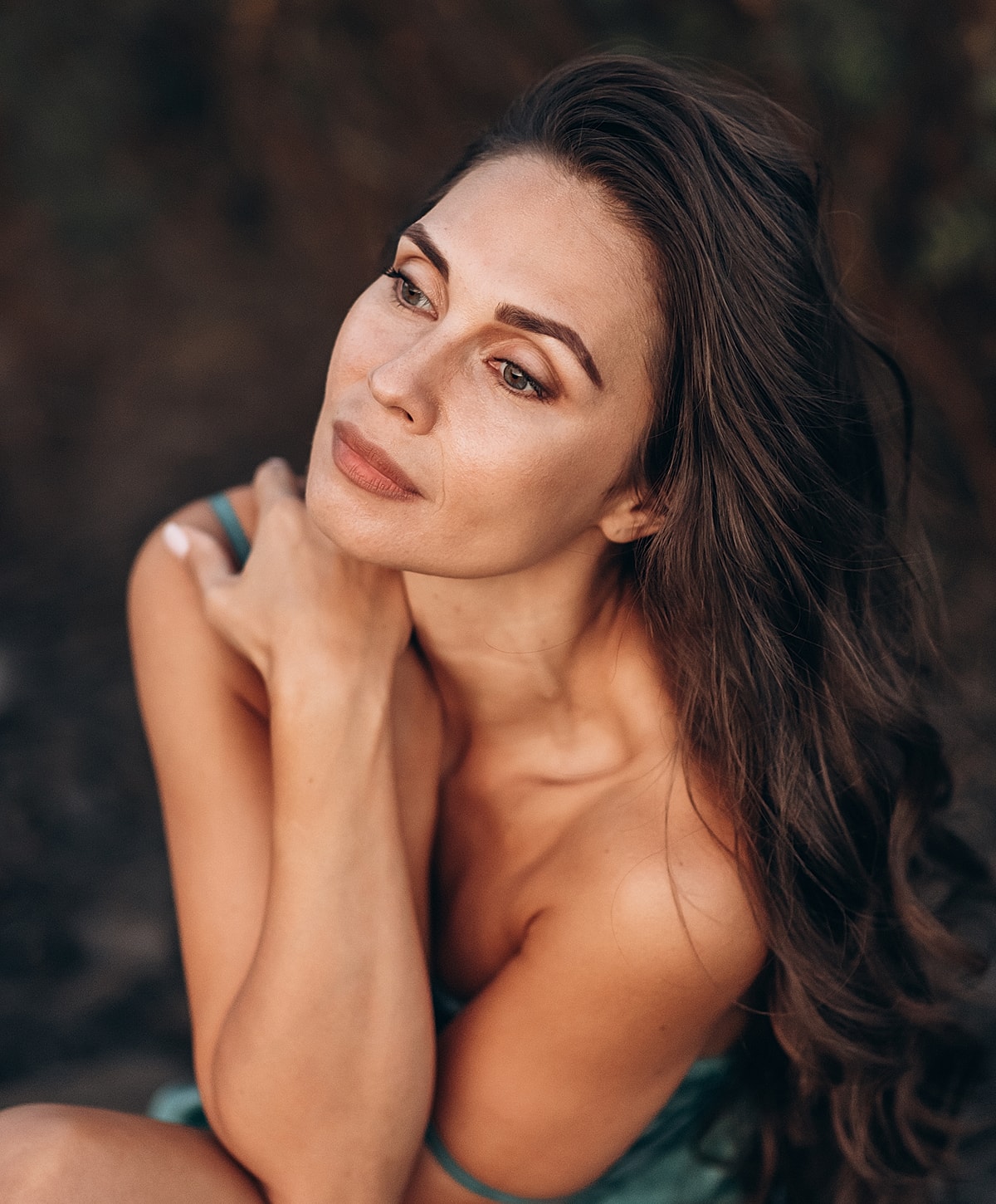 Woman with long hair in contemplative pose.