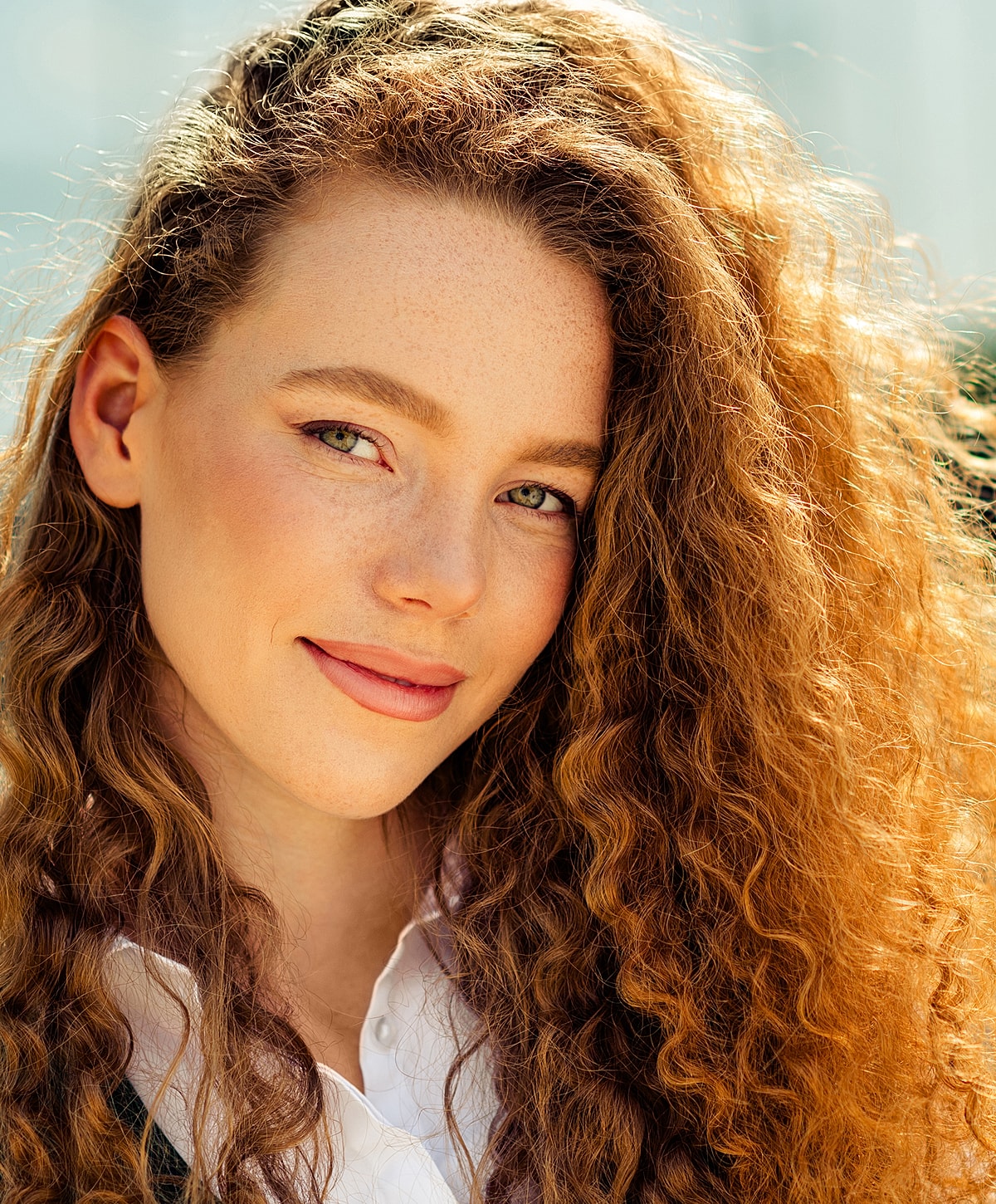 Young woman with curly hair and freckles.