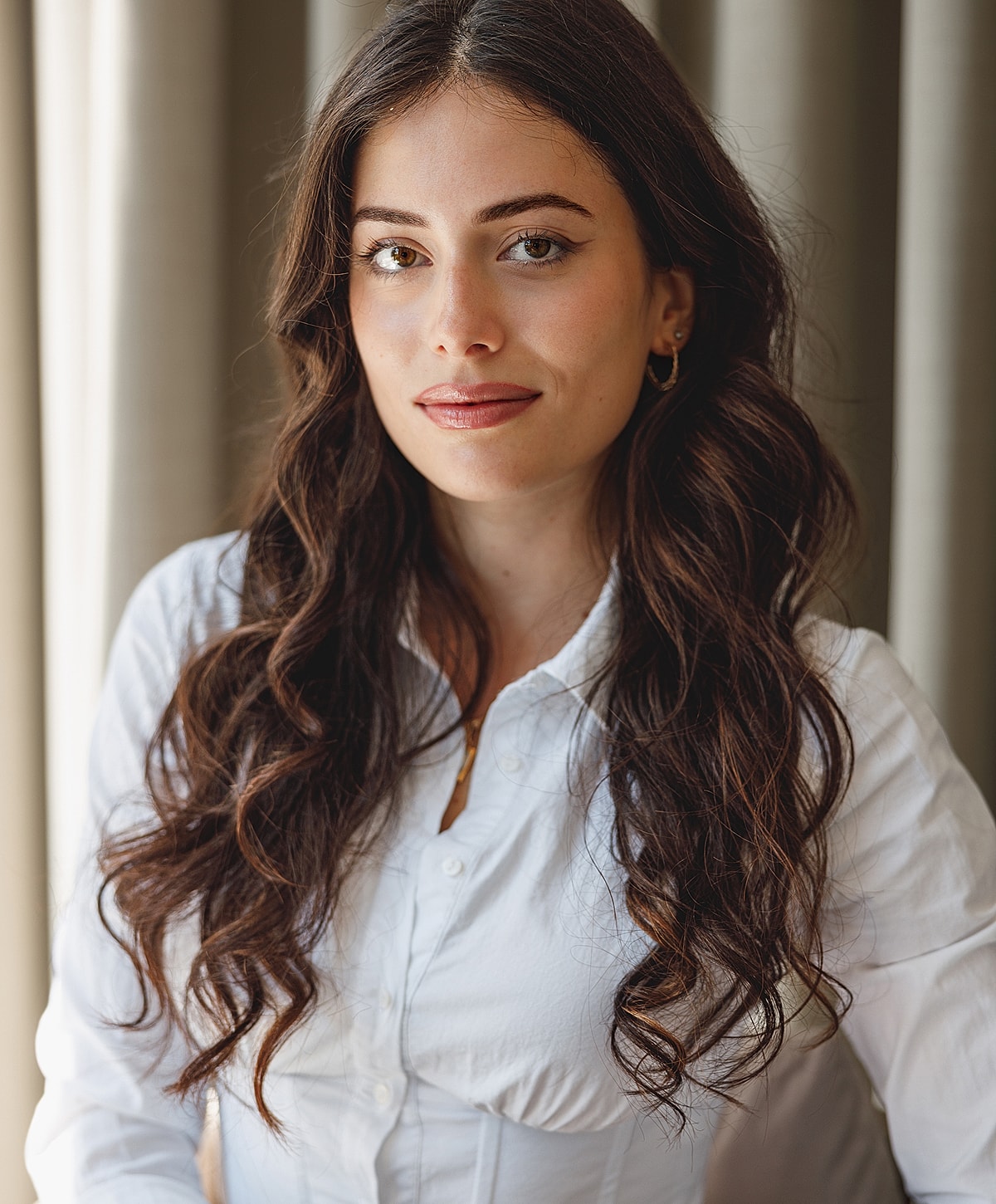 Woman with long, wavy hair in white shirt.