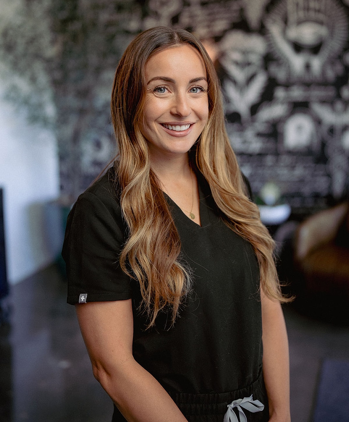 Smiling woman in a black medical uniform.