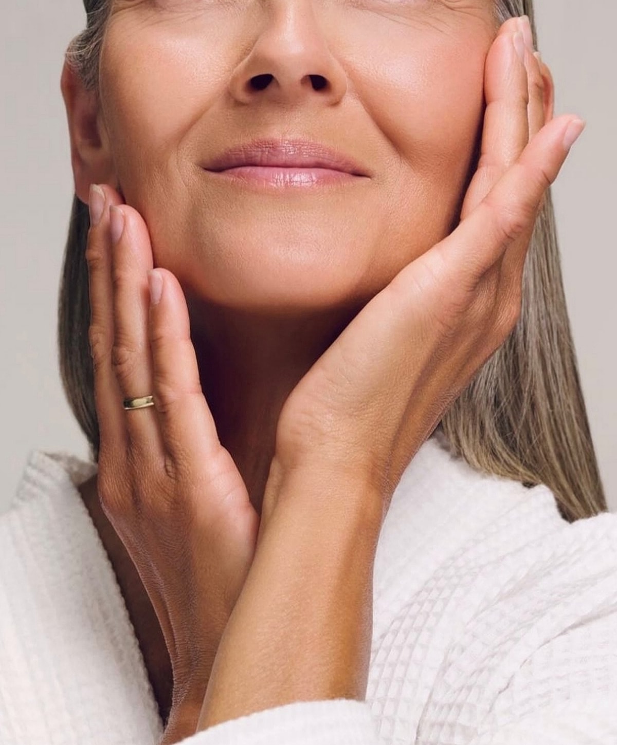 Woman gently touching her face with hands.