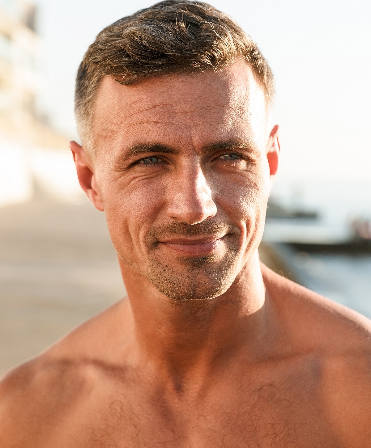 Smiling man with short hair by the beach.