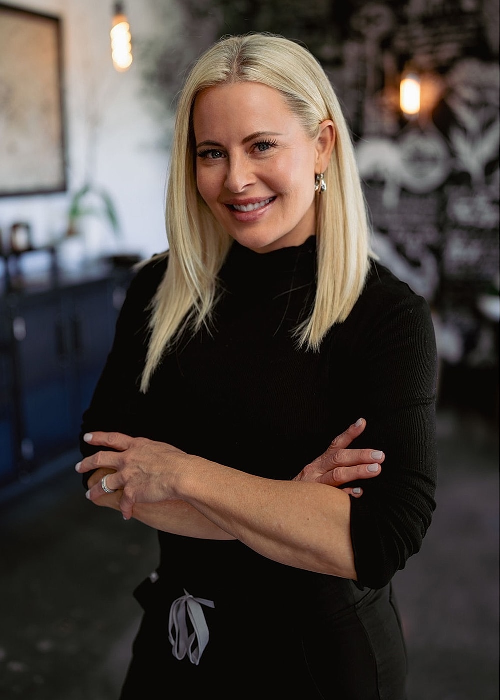 Smiling woman with blonde hair in black outfit.