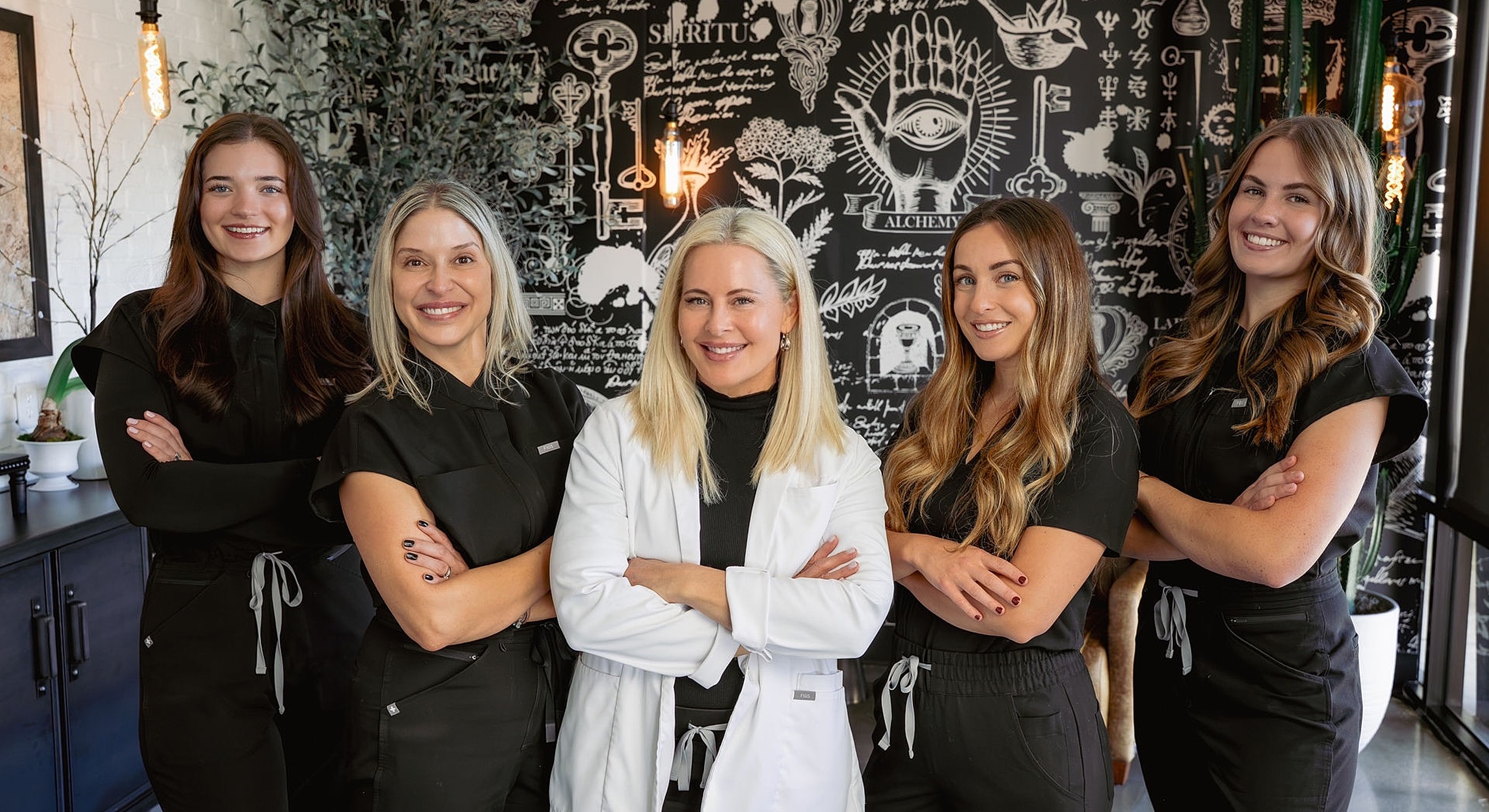 Five professionals posing in a stylish setting.