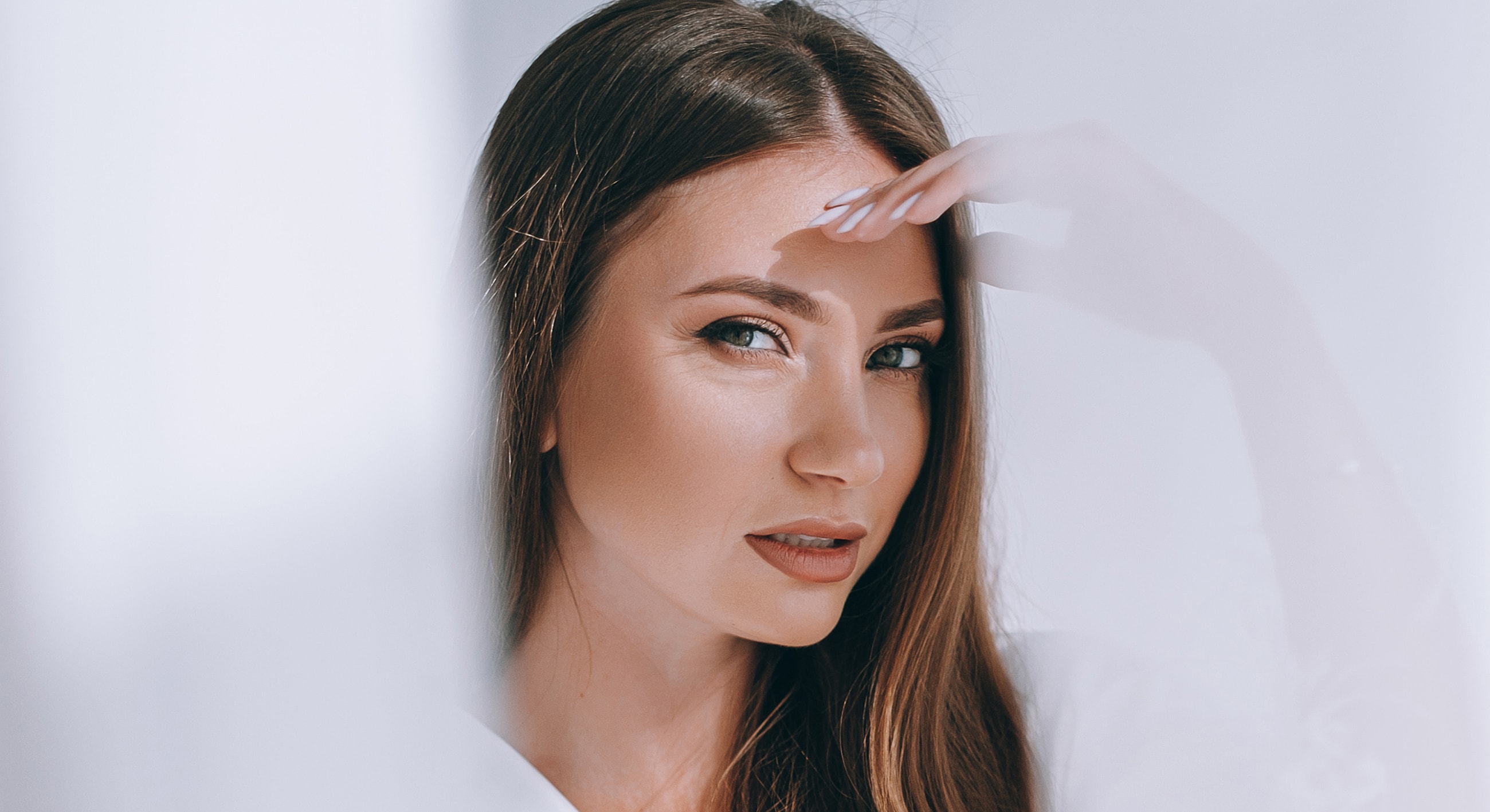 Woman with long hair looking thoughtfully at camera.
