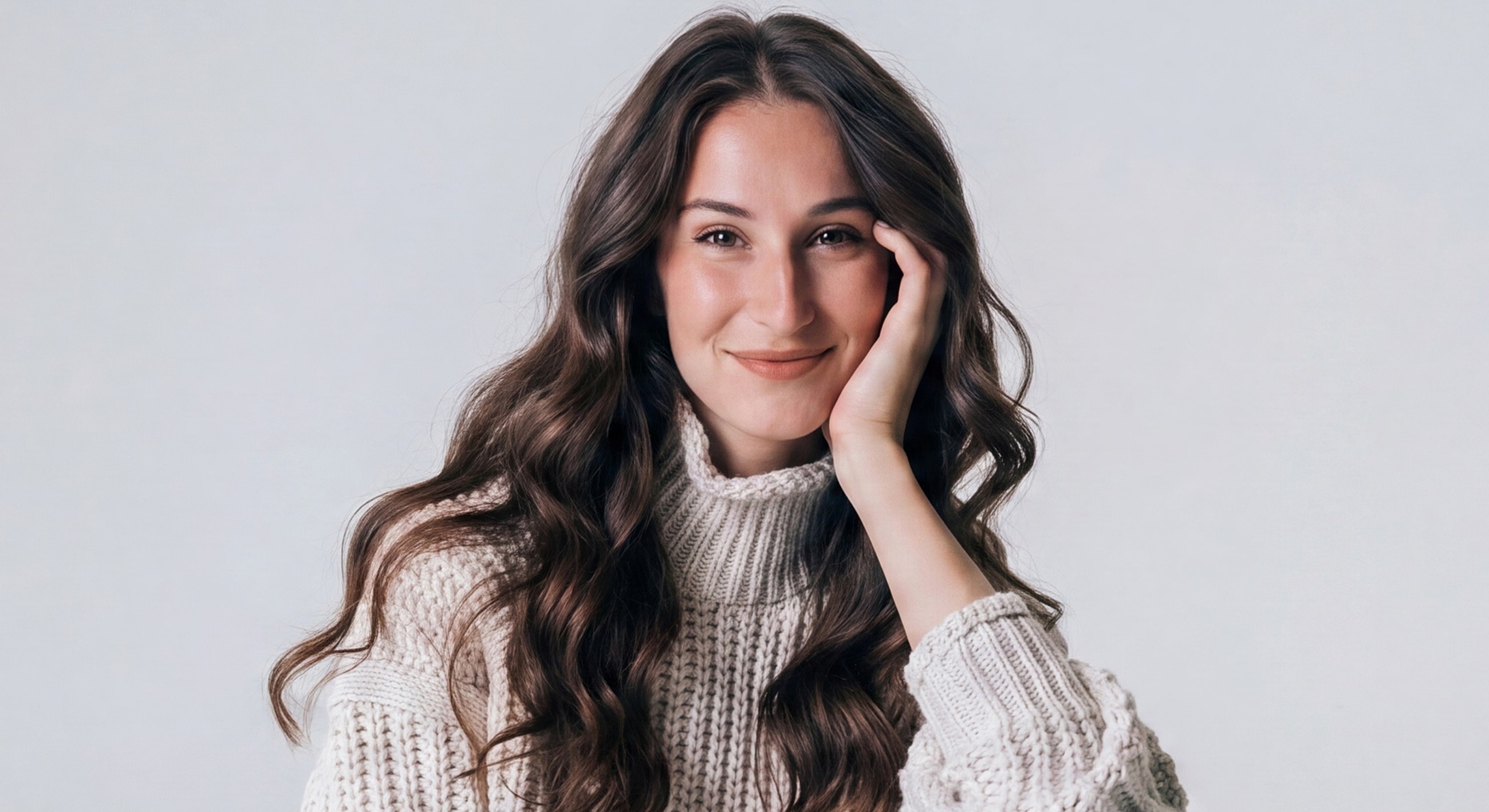 Smiling woman in cozy sweater, light background.