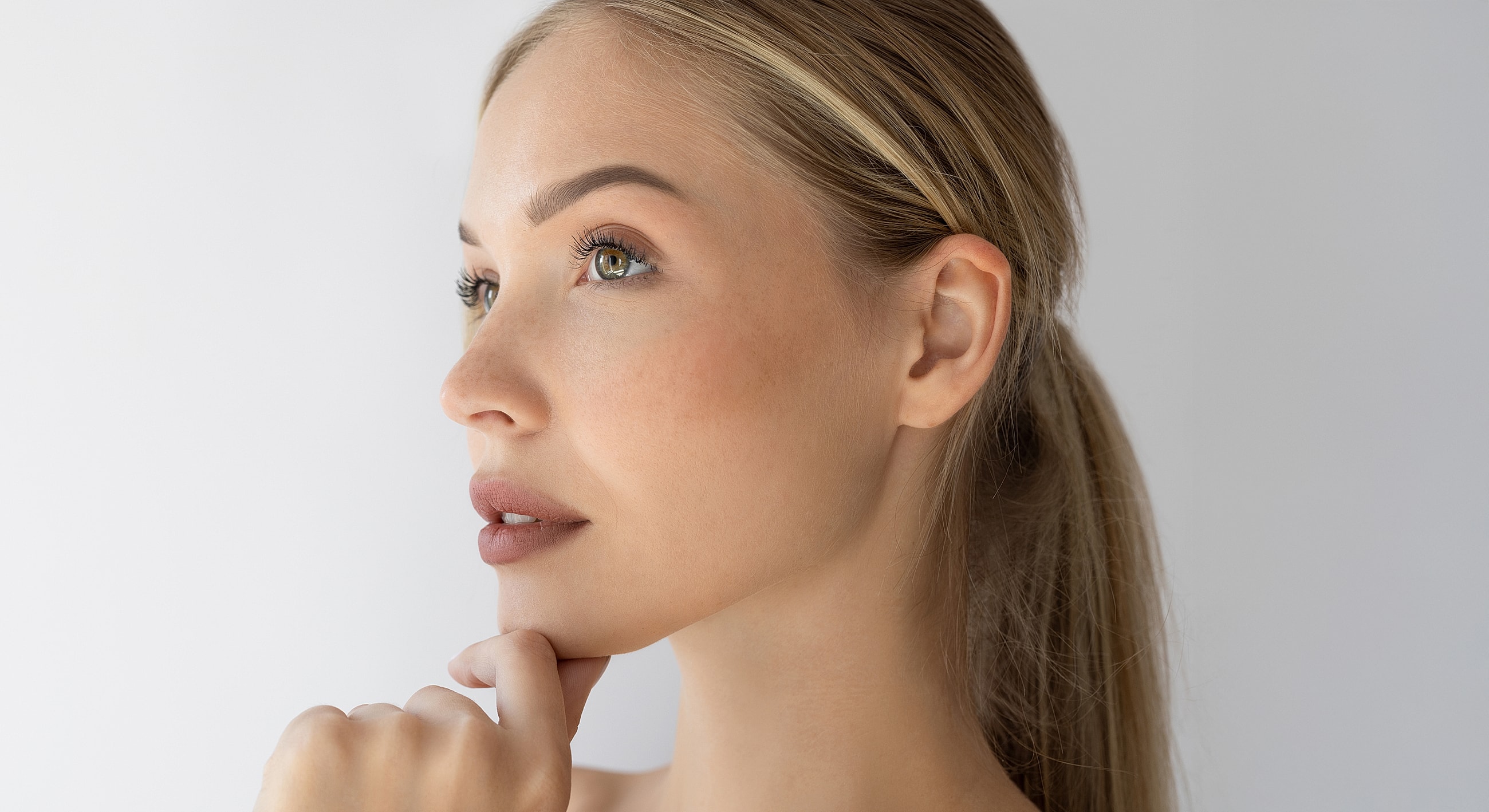 Woman in profile touching chin thoughtfully.